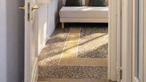 A narrow hallway with a bench, a clock on the wall, and a door with a golden handle. - Bright, comfortable and panoramic apartment! (Roma)