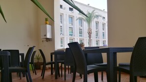 Terraza con mobiliario de mimbre y vista a un edificio con unidades de aire acondicionado.