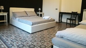 Un dormitorio con cama, mesitas de noche, un escritorio y una silla.