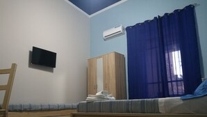 Un dormitorio con cama, armario de madera, televisor y aire acondicionado.