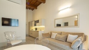 A modern living room with a sofa, a TV, a kitchen area, and a dining table. - Carapelli 2 Fabulous apartment for up to four guests (florence)