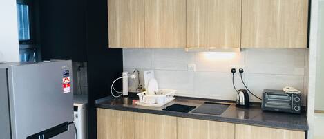 A modern kitchen with wooden cabinets, a stainless steel refrigerator, a toaster, and a kettle.
