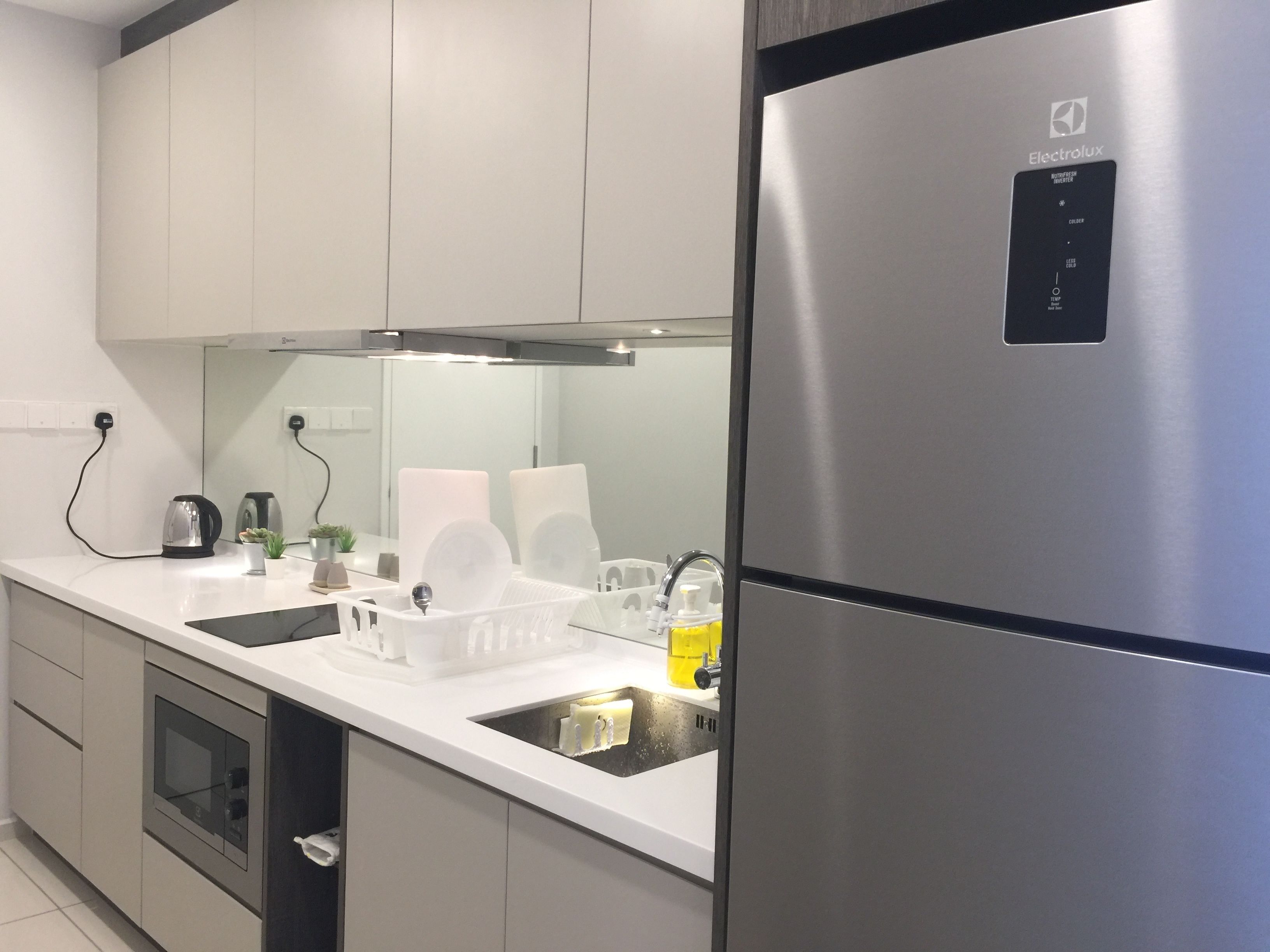 A modern kitchen with stainless steel appliances, white cabinetry, and a built-in oven.