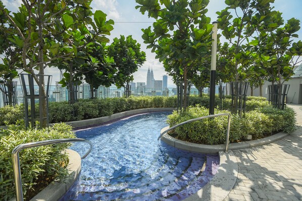 A swimming pool with a view of a city skyline, surrounded by trees and greenery. - Robertson Suites Kuala Lumpur (Kuala Lumpur)