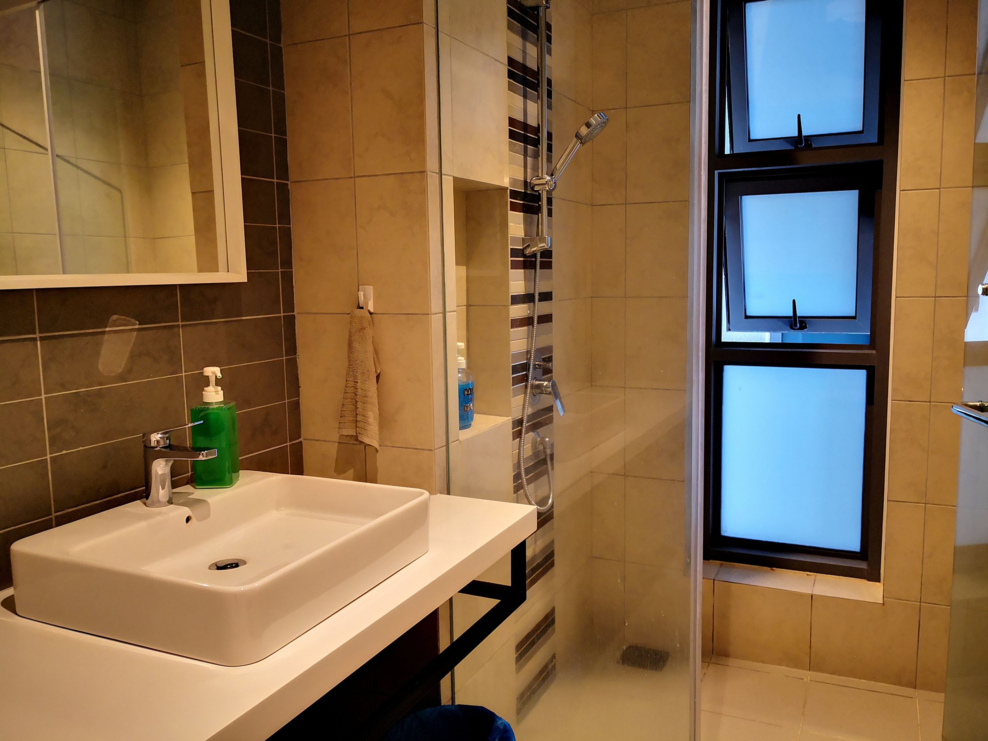 A bathroom with a white sink, a glass shower enclosure, and a mirror above the sink.