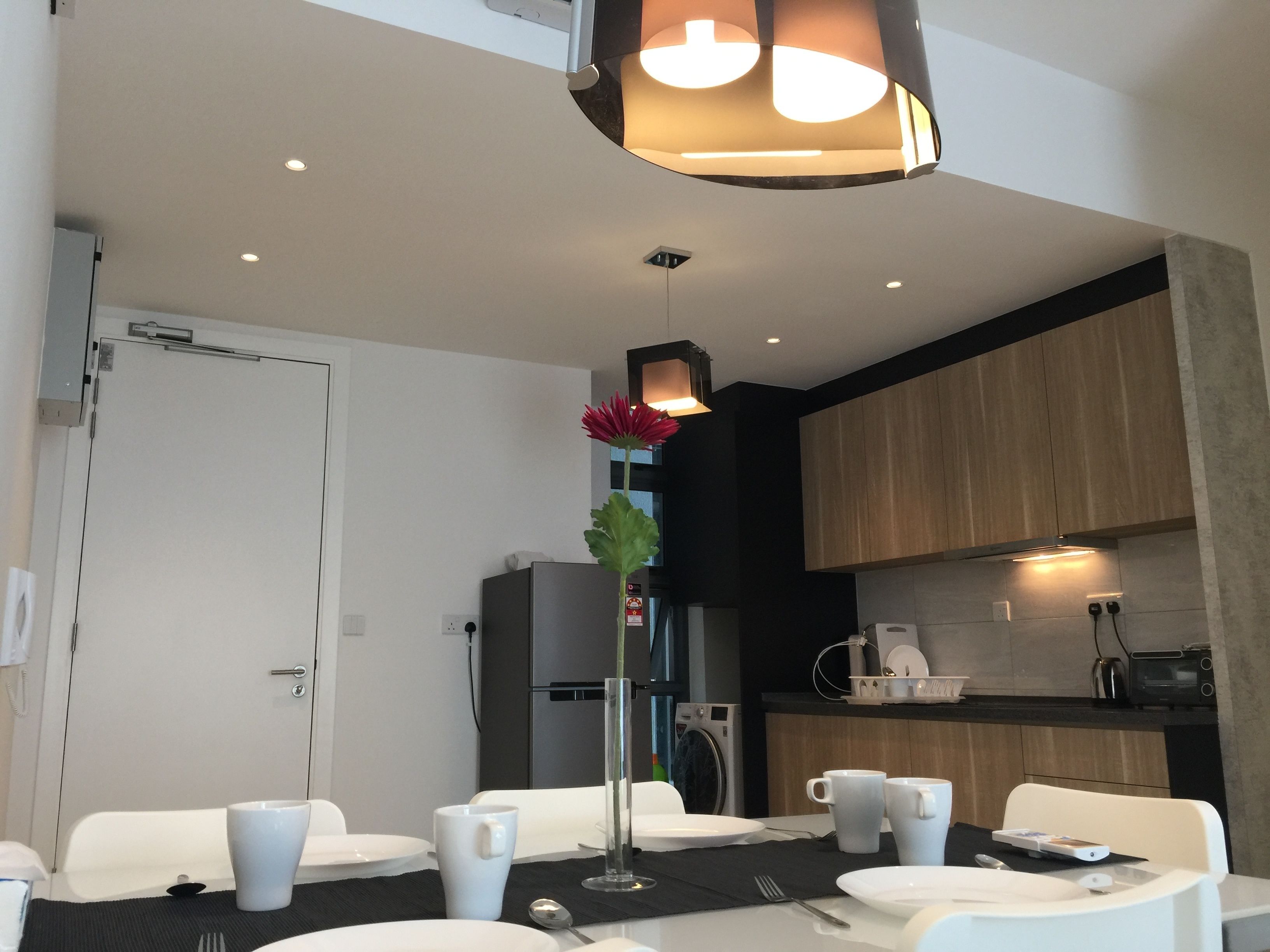 Een moderne eetruimte met witte stoelen, een centrale tafel en een hanglamp.
