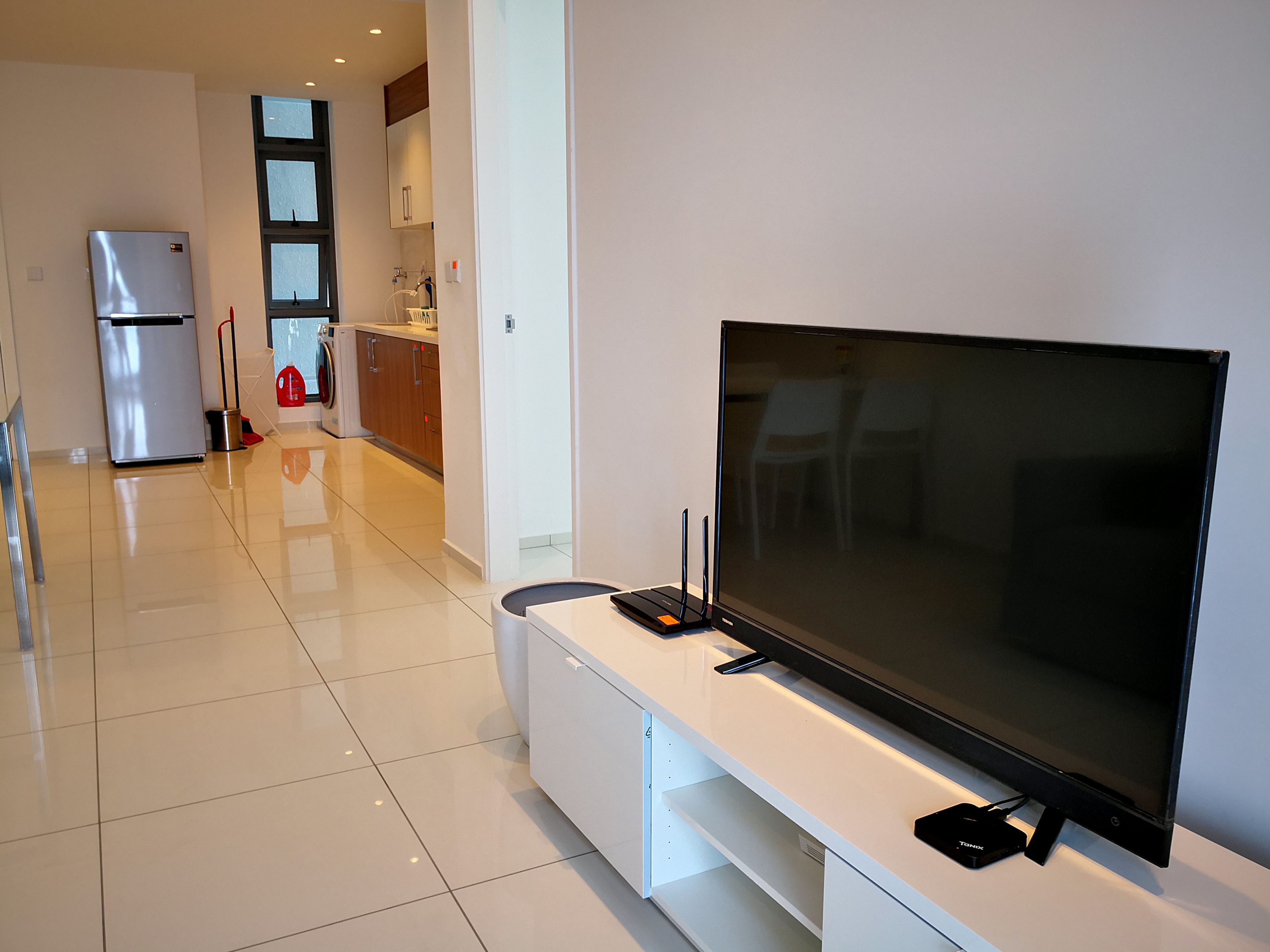 A modern living room with a large flat-screen TV, a built-in sound system, and a sleek white entertainment unit.