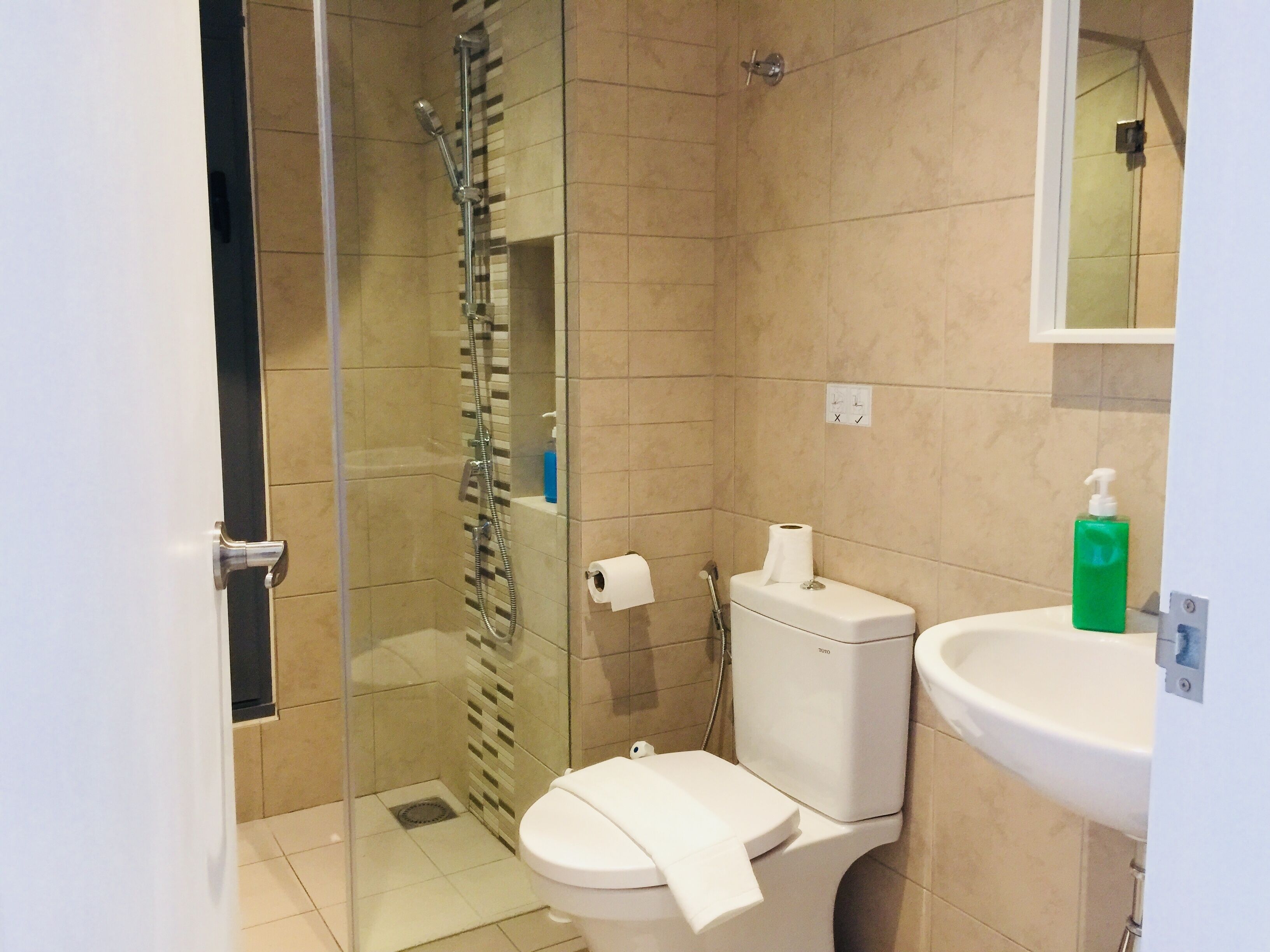 A bathroom with a glass-enclosed shower, a toilet, and a sink.