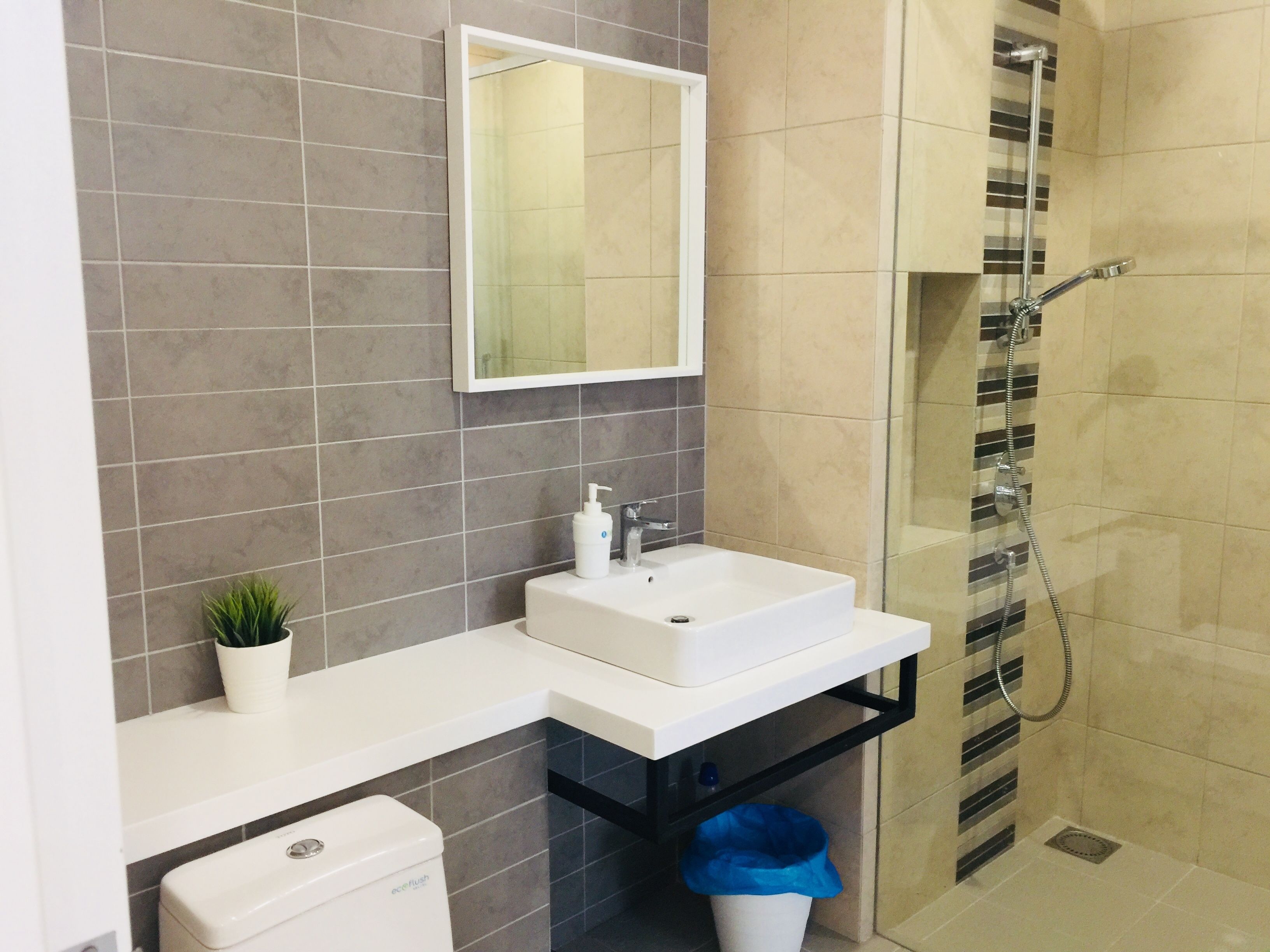Un baño moderno con un lavamanos blanco, un espejo, ducha e inodoro.