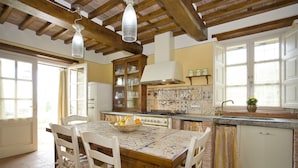 A kitchen with a tiled backsplash, wooden cabinets, and a dining table with chairs.