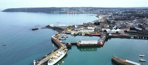 An aerial view of a coastal town with a marina, harbor buildings, and a prominent church.