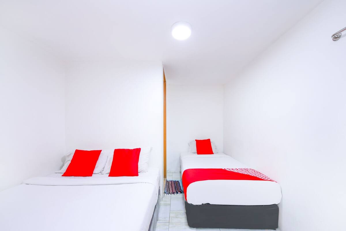 Een kleine, schone kamer met twee bedden, elk met rode en witte lakens.