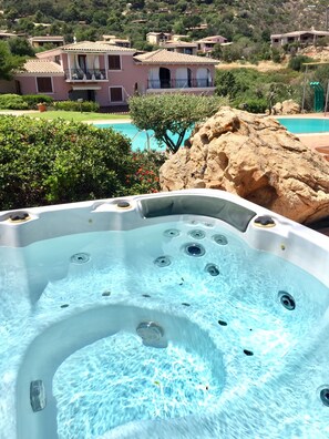 Ein Whirlpool mit Blick auf einen Pool und eine Hügelside mit Häusern.