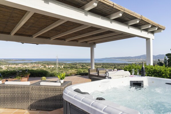 Un jacuzzi avec vue sur la mer, un espace salon extérieur et une pergola.