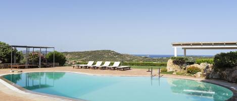 Una piscina con sillas de descanso y vistas al mar.