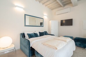 Ein Schlafzimmer mit einem Bett, einem Spiegel, einem Kleiderschrank und einem Fernseher.