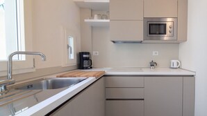 Une cuisine moderne équipée d’un évier en acier inoxydable, d’un four à micro-ondes et d’une machine à café.