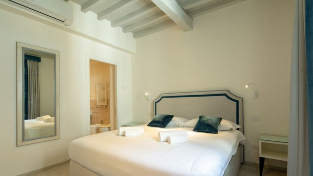 Une chambre d’hôtel avec un grand lit, un miroir, une salle de bain et une table de chevet.