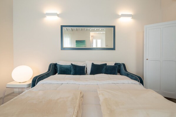 A bedroom with a bed, bedside lamps, a mirror, and a wardrobe.