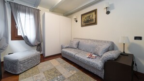 Un salon avec un canapé, un banc, une lampe et un tableau encadré au mur.