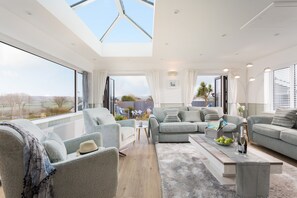 Un salon moderne doté d’une grande fenêtre, d’un ensemble de canapés, d’une table basse et offrant une vue sur l’extérieur.