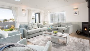 Een ruime woonkamer met een hoge plafond, een open haard en een groot raam.