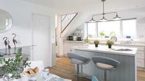 Een moderne keuken met een centraal eiland, barkrukken en uitzicht op de woonkamer.