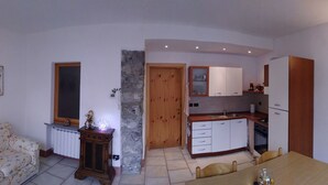 A compact living space with a sofa, a small table, a kitchen area with cabinets, and a television. - Lake Iseo in Esmate:The House of Fairies CIR.016200CNI00013 CIN IT016200C2UAHS6HFE (Solto Collina)