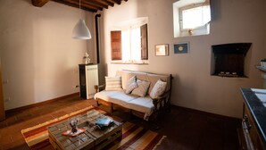 Uma sala de estar aconchegante com teto de madeira, um sofá, uma mesa de centro de vidro e uma lareira.