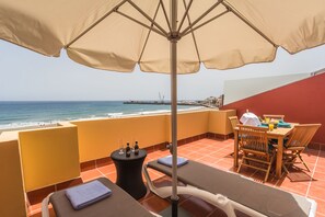 A balcony with a view of the beach, a table with chairs, and lounge chairs. - Ocean View Penthouse II. Beachfront Wifi & A / C. 23m2 private terrace. (Gran Tarajal)