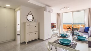 Un salon moderne avec un coin repas, une armoire blanche et une vue sur la mer.