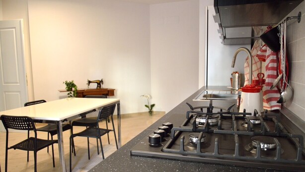 Une cuisine compacte équipée d’une cuisinière à gaz, d’un évier et d’un coin repas avec une table et des chaises.