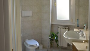 Une salle de bain avec des toilettes, un lavabo et une fenêtre.