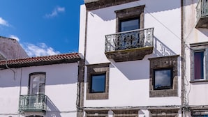 Una calle empedrada con un edificio blanco que tiene un balcón y una tienda a la derecha.