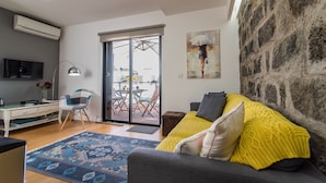 Una sala de estar con un sofá, un escritorio, una silla y un ventanal grande.