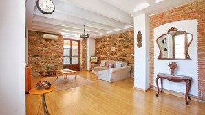 A living room with a stone wall, wooden flooring, a sofa, a coffee table, and a mirror.