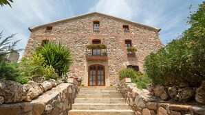A stone building with a central entrance, multiple windows, and a staircase leading to the entrance.