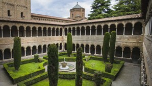 A courtyard with a central fountain, surrounded by neatly trimmed hedges and tall trees.