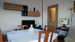 A small, tidy room with a dining table, chairs, a TV, and a computer on a desk. - Apartment in villa with garden CIN IT032003C2BP5JM2B2 (Muggia (TS))