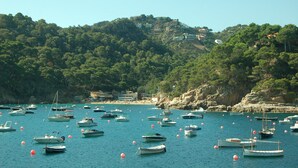 A coastal area with numerous boats anchored in calm waters, surrounded by lush green hills and rocky cliffs. - Luxury, self contained, airconditioned studio with private terrace & use of pool (Begur)