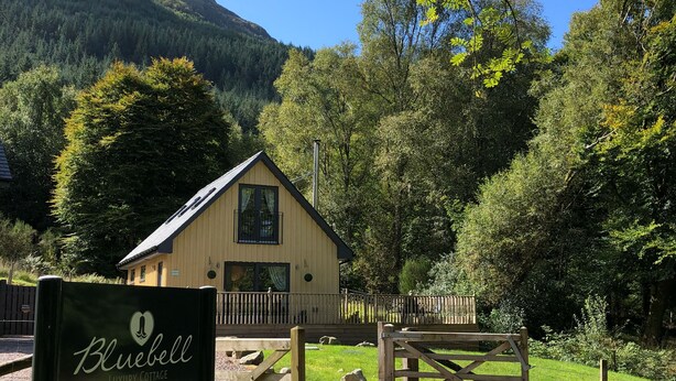 Eine rustikale Lodge mit Holzfassade, umgeben von üppigem Grün und Bergen.