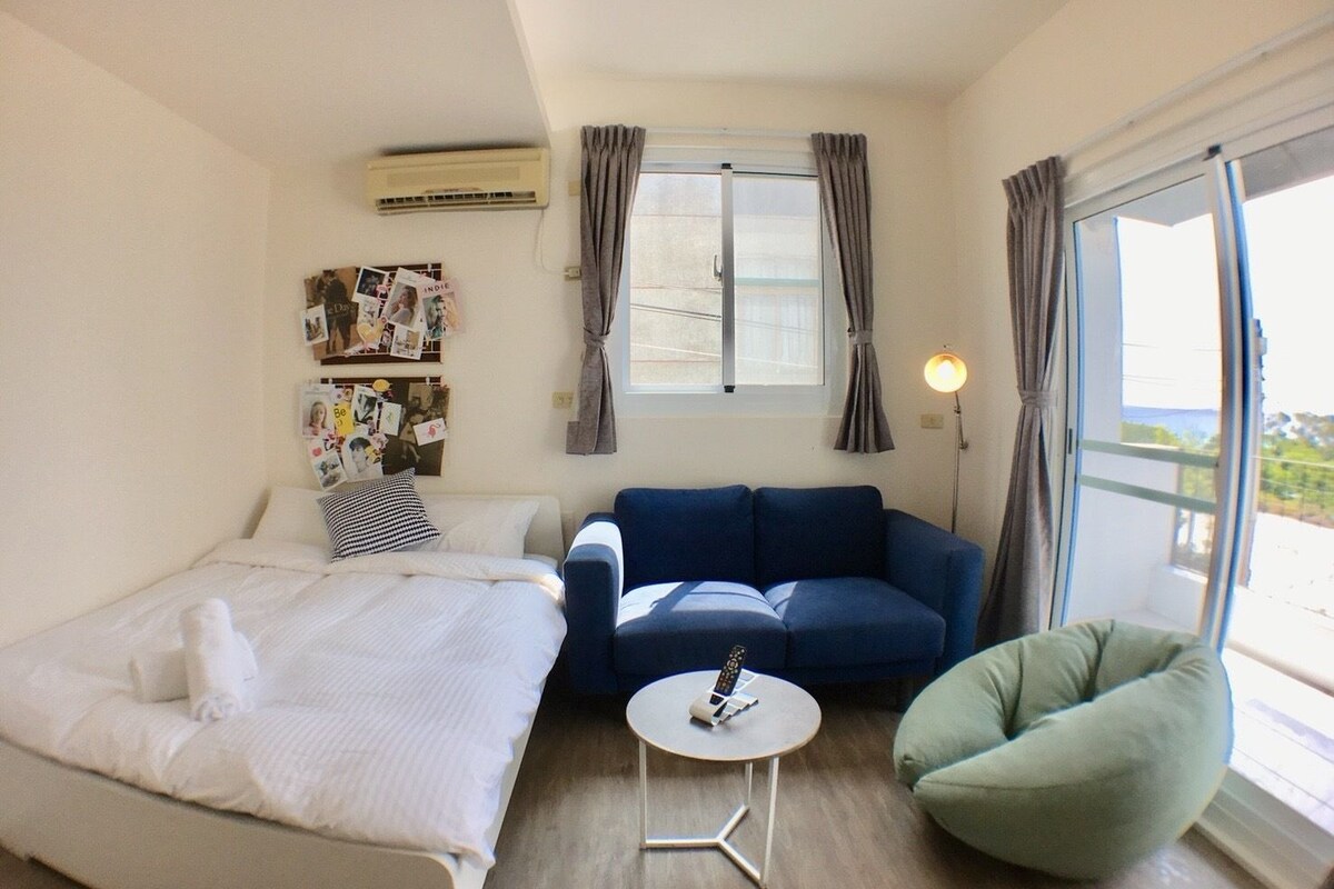 A room with a bed, a blue sofa, a small round table, and a green chair.