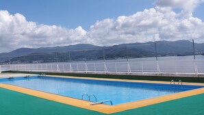 Une piscine avec vue sur les montagnes et donnant sur un plan d’eau.