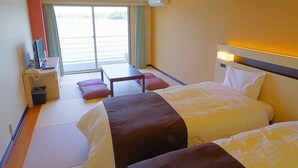 Une chambre d’hôtel avec deux lits, un bureau, une chaise, une petite table et une vue sur l’extérieur grâce à une grande fenêtre.