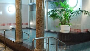 Un hall d’entrée propre et moderne, avec un sol à carreaux, une plante en pot et un ascenseur en verre.