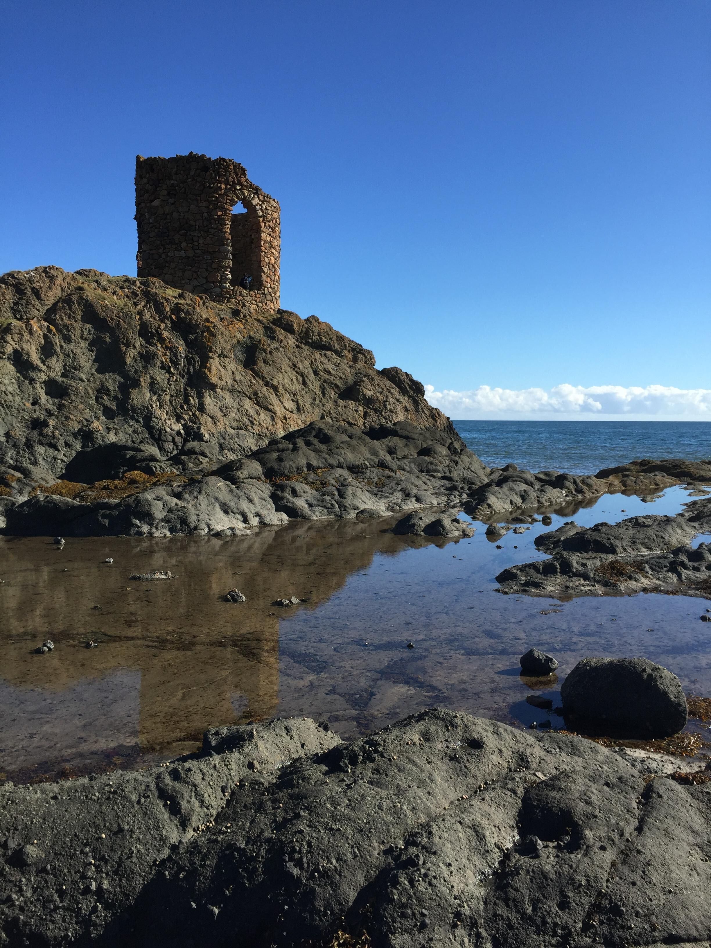 Un paisaje costero rocoso con una estructura de torre de piedra.