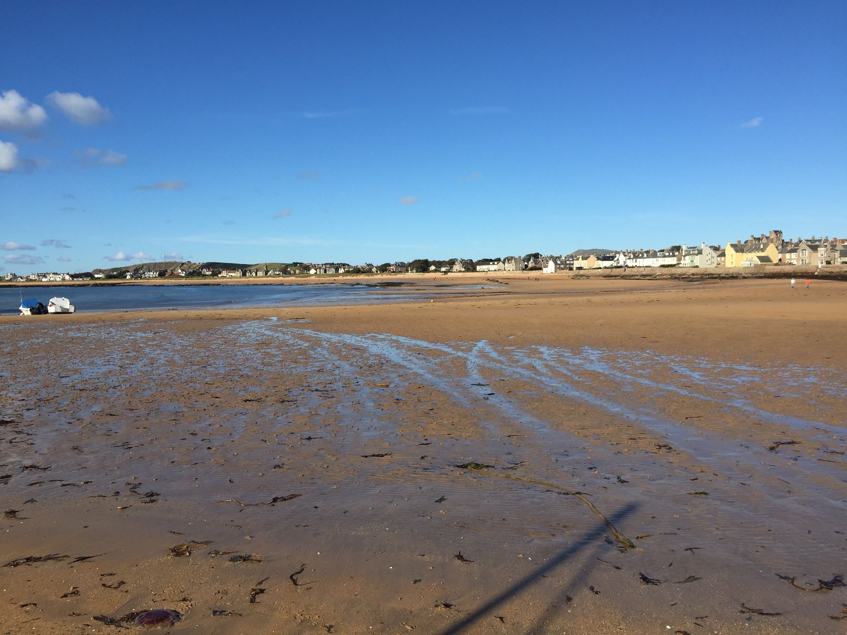 A wide sandy beach with a clear sky and calm sea.