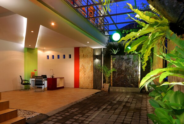A reception area with a desk, chairs, and a staircase leading to an upper level. - Valomia Guest House (Denpasar)