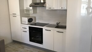 Ett modernt kök med vita skåp, en rostfri köksfläkt, en mikrovågsugn, en diskho och en diskmaskin.