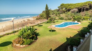A pool with a view of the beach, surrounded by greenery and a fence. - A UNIQUE PARADISE in Royal Beach, Mijas beach (Calahonda - Mijas Costa)